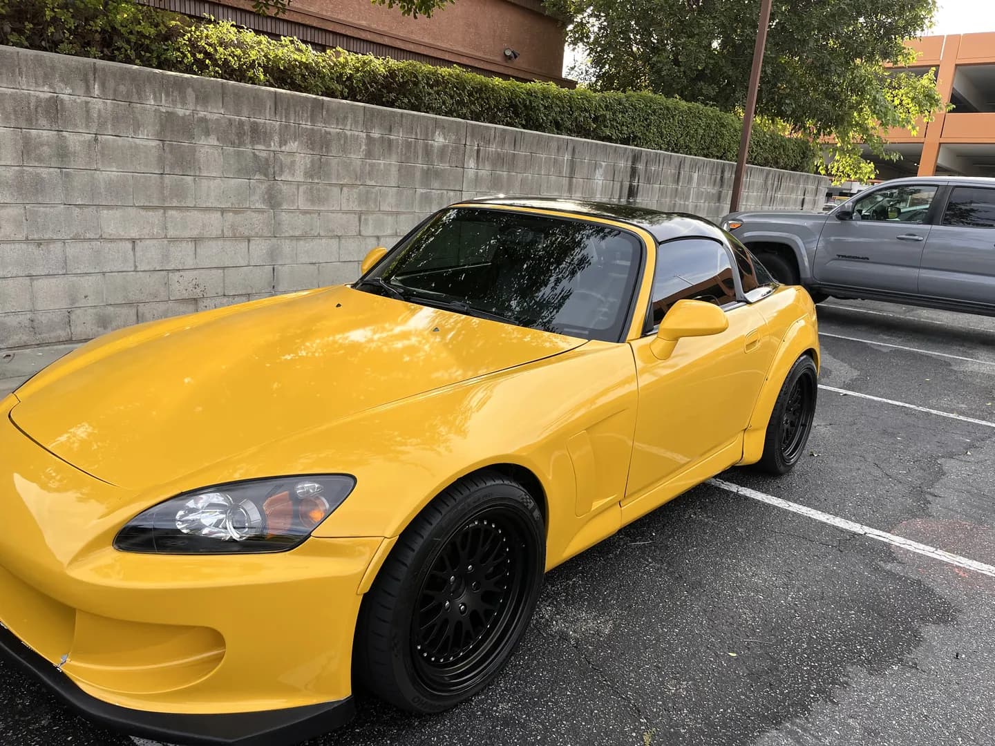 Yellow Honda roadster with a black hardtop and black wheels